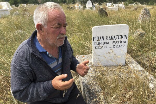In this Thursday, July 25, 2019 photo, Satilmis Karatekin a distant cousin of Boris Johnson prays at the grave of a family member, in Kalfat, a village in the Cankiri province, 100 kilometers (62 miles) north of the Turkish capital Ankara, Turkey. A village in central Turkey where Boris Johnson can trace his Turkish ancestry to is abuzz with excitement and pride over the news that a man they see as one of their own has become the new prime minister of Britain. Residents of the mainly farming village of Kalfat, north of the Turkish capital Ankara, gathered to celebrate after Johnson won a Conservative Party leadership contest and become the country’s leader. They hope he will visit soon. (AP Photo/Mehmet Guzel)