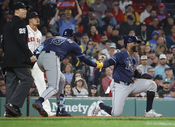 Tampa Bay Rays' Yandy Díaz is congratulated by teammate Junior Caminero (13) after scoring on a single by Jonathan Aranda during the seventh inning of a baseball game against the Boston Red Sox at Fenway Park, Monday, June 9, 2025, in Boston. (AP Photo/Mary Schwalm)