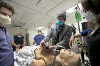 This April 22, 2020 photo provided by the Oregon Health & Science University, showing left to right Evan Fontaine, Dr. Albert Chi, Dennis Child, Whitney Menzel, and Dr. Stephanie Nonas test out a new ventilator created with 3D-printing technology at the Oregon Health & Science University, in Portland, Ore. Amid a global shortage of ventilators, a team from Oregon Health & Science University has come up with a low-cost version produced with 3D-printing technology, the university announced Friday, April 24, 2020. (Kristyna Wentz-Graff/OHSU via AP)