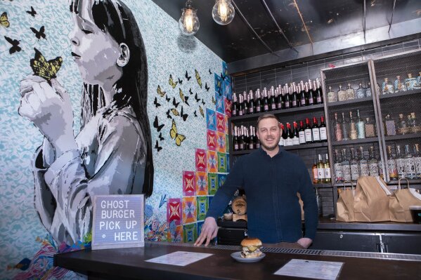 Josh Phillips, the co-owner of Espita, a stylish Mexican restaurant, displays a Ghostburger at his restaurant in downtown Washington, Monday, Feb. 15, 2021. Phillips opened a delivery-only brand called Ghostburger in August to keep Espita’s kitchen running through the winter. He chose burgers because he wanted to reach new customers at a lower price point than Espita. It’s been so successful that Phillips is now scouting for locations for standalone Ghostburger restaurants. (AP Photo/Jose Luis Magana)