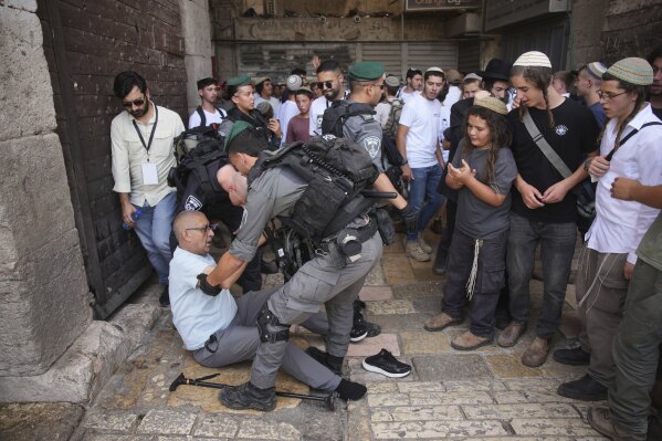 Israeli police officers assist a Palestinian man after he was pushed by Israelis as they mark Jerusalem Day, an Israeli holiday celebrating the capture of east Jerusalem in the 1967 Mideast war, in Jerusalem's Old City, Monday, May 26, 2025. (AP Photo/Ohad Zwigenberg)