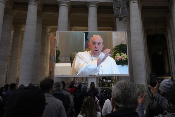 On Sunday, November 26, 2023, a giant screen broadcasts Pope Francis giving his blessing during the Angelus afternoon prayer from the chapel of the hotel on the Vatican grounds, where he lives.  Pope Francis says he has inflammation in his lungs, but will be released this weekend.  Dubai for climate change conference.  A day after the Vatican said he was suffering from mild flu, Francis skipped his weekly Sunday appearance at a window overlooking St. Peter's Square.  (AP Photo/Alessandra Tarantino)