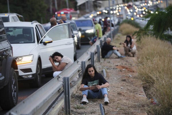 People take cover on the side of a highway as a siren sounds a warning following a missile that was launched from Yemen, in Tel Aviv, Israel, Tuesday, May 13, 2025. (AP Photo/Ohad Zwigenberg)