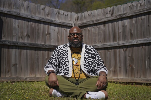 Lama Rod Owens sits in the yard of his childhood home in Rome, Georgia, on Saturday, March 30, 2024. Owens is an influential voice in a new generation of Buddhist teachers, respected for his work focused on social change, identity and spiritual wellness. (AP Photo/Jessie Wardarski)