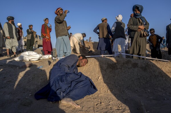 An Afghan man rests his head on the grave of his wife who died due to an earthquake and talks to her at a burial site, in Zenda Jan district in Herat province, western of Afghanistan, Monday, Oct. 9, 2023. Saturday's deadly earthquake killed and injured thousands when it leveled an untold number of homes in Herat province. (AP Photo/Ebrahim Noroozi)