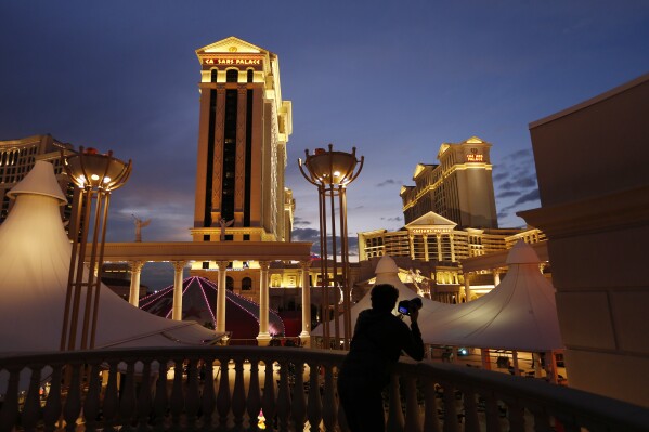 FILE - A man takes pictures of Caesars Palace hotel and casino in Las Vegas, Jan. 12, 2015. Casino company Caesars Entertainment has joined Las Vegas gambling giant MGM Resorts International in reporting a recent cyberattack. But while MGM Resorts computer systems were still down, Caesars told federal regulators on Thursday, Sept. 14, 2023, that its casino and online operations were not disrupted. (AP Photo/John Locher, File)