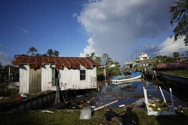 FILE - A cottage belonging to the Ellison family teeters over a canal, alongside the remnants of the family's destroyed business, Ed's Baithouse and Marina, in Horseshoe Beach, Fla., Aug. 31, 2023, one day after the passage of Hurricane Idalia. Americans nationwide face hefty increases in their homeowner’s insurance premiums in the coming years, a report by the First Street Foundation said on Wednesday, Sept. 20, as climate change intensifies floods, wildfires and storms in ways insurance companies are simply unable to keep up with. (AP Photo/Rebecca Blackwell, File)