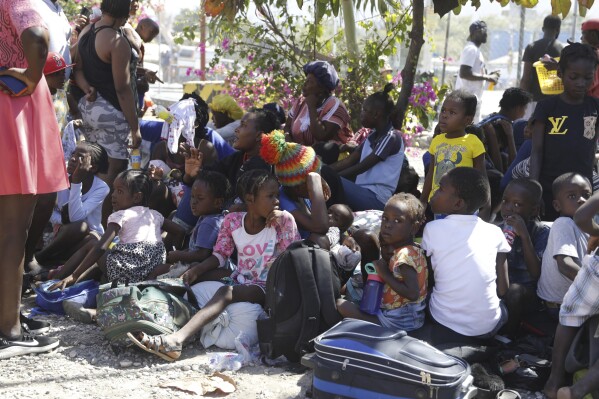 FILE - Children and their guardians gather outside a police station after they fled their homes in Cite Soleil due to gang violence, in Port-au-Prince, Haiti, Feb. 12, 2024. Indiscriminate violence in Haiti is escalating — especially in the capital and surrounding region — with armed gangs carrying out killings and acts of sexual violence, Ulrika Richardson, the United Nations humanitarian coordinator in the conflict-wracked Caribbean nation, said Wednesday, Feb. 28, 2024. (AP Photo/Odelyn Joseph, File)