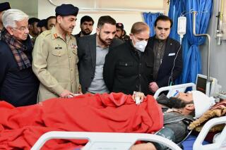 In this handout photo released by Press Information Department, Pakistan's Prime Minister Shehbaz Sharif, second right, and Army Chief, Gen. Asim Munir, second left, talk with an injured victim of suicide bombing inside a mosque, during their visit to hospital, in Peshawar, Pakistan, Monday, Jan. 30, 2023. A suicide bomber struck Monday inside a mosque in the northwestern Pakistani city of Peshawar, killing multiple people and wounding scores of worshippers, officials said. (Press Information Department vis AP)