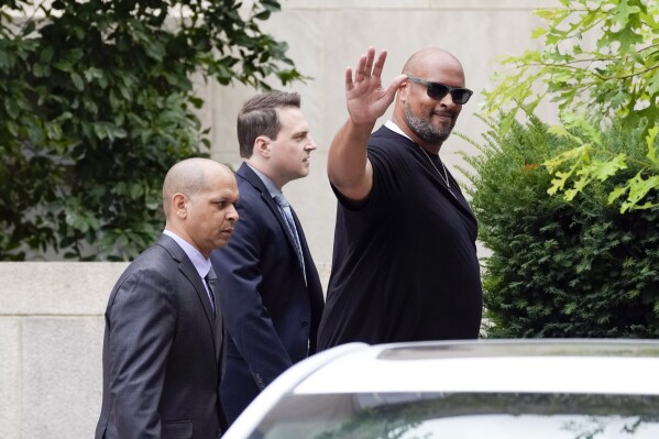 U.S. Capitol Police Sgt. Harry Dunn, with U.S. Capitol Police Sgt. Aquilino Gonell, left, and Washington Metropolitan Police Department officer Daniel Hodges, center, waves after former President Donald Trump arrived at the E. Barrett Prettyman U.S. Federal Courthouse, Thursday, Aug. 3, 2023, in Washington, to face a judge on federal conspiracy charges alleging Trump conspired to subvert the 2020 election. (AP Photo/Alex Brandon)