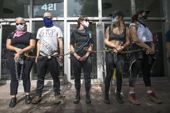New Orleans Renters Rights Assembly protesters chain themselves together outside an entrance to First City Court near New Orleans City Hall on Thursday, July 30, 2020. (Chris Granger/The Advocate via AP)