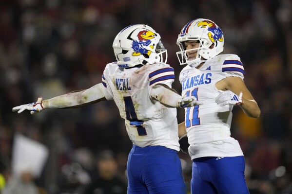 Kansas running back Devin Neal (4) celebrates with teammate wide receiver Luke Grimm (11) at the end of an NCAA college football game against Iowa State, Saturday, Nov. 4, 2023, in Ames, Iowa. Kansas won 28-21. (AP Photo/Charlie Neibergall)