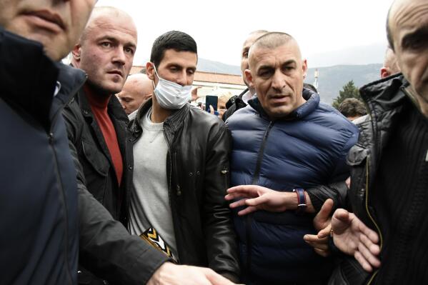 Serbian tennis player Novak Djokovic, center, with mask arrives in the municipal building in Budva, Montenegro, Friday, Jan. 28, 2022. Djokovic arrived to receive a plaque declaring him an honorary citizen of the town. (AP Photo/Risto Bozovic)