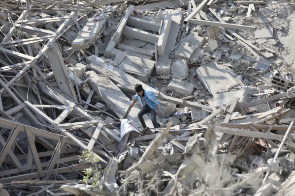Palestinians walk through the destruction left by the Israeli air and ground offensive on the Gaza Strip in Gaza City, Saturday, Feb. 10, 2024. (AP Photo/Mohammed Hajjar)