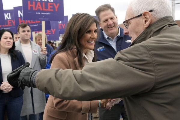 Republican presidential candidate former U.N. Ambassador Nikki Haley, center, and N.H. Gov. Chris Sununu, behind right, greet people, Tuesday, Jan. 23, 2024, near a polling site at Winnacunnet High School in Hampton, N.H. (AP Photo/Steven Senne)
