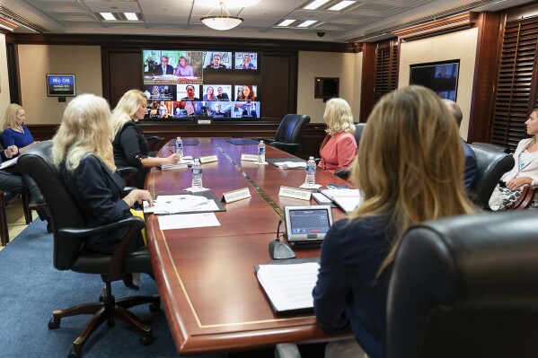In this June 30, 2020 photo provided by the White House, first lady Melania Trump, joined by Health and Human Services Secretary Alex Azar, Senior Counselor to the President Kellyanne Conway and White House senior advisers, participate in a roundtable discussion on foster care and strengthening America's child welfare system, in the Situation Room in the White House in Washington. On screen, middle row at right is Adoption-Share founder and CEO Thea Ramirez. Trump spotlighted Ramirez's work at the foster care event. (Andrea Hanks/The White House via AP)