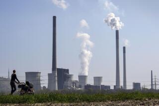 FILE - A mother pushes a stroller in front of the Scholven coal-fired power station, owned by Uniper, in Gelsenkirchen, Germany, March 28, 2022. The world remains “far behind” and is not doing nearly enough to reach any of the global goals limiting future warming, a United Nations report said. (AP Photo/Martin Meissner, File)