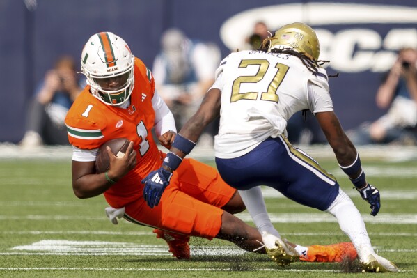 Miami quarterback Cam Ward (1) slides before being tackled by Georgia Tech defensive back Omar Daniels (21) during the first half of an NCAA college football game, Saturday, Nov. 9, 2024, in Atlanta. (AP Photo/Jason Allen)