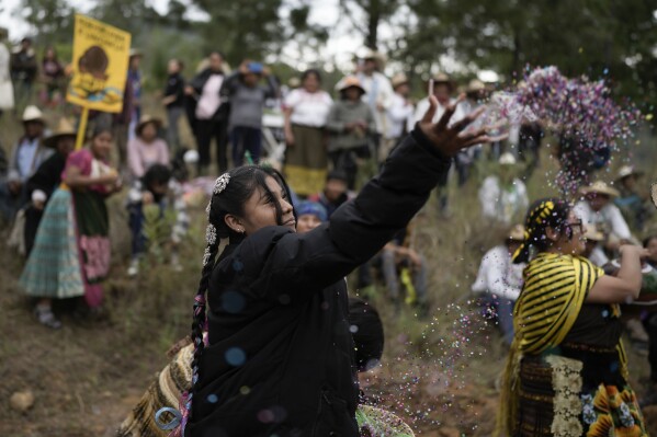 A Purepecha Indigenous woman tosses confetti during a rest stop by a group walking from Erongaricuaro, where residents kept a flame alive for one year and are taking it to Ocumicho in Michoacan state, Mexico, Wednesday, Jan. 31, 2024. To mark the new year, based on an ancient lunar calendar, a new flame will be lit during a “New Fire” ceremony on Feb. 2. (AP Photo/Eduardo Verdugo)