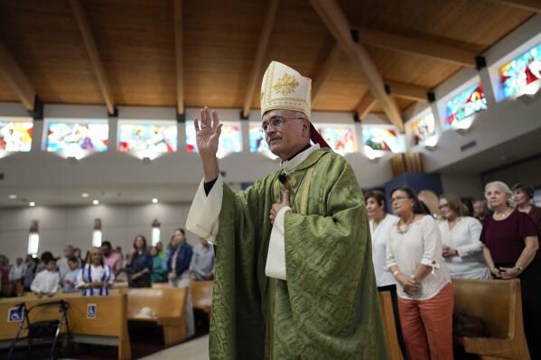 Rev. Silvio Baez, auxiliary bishop of Managua, Nicaragua, waves to parishioners as he enters to perform Mass at St. Agatha Catholic Church, which has become the spiritual home of the growing Nicaraguan diaspora, Sunday, Nov. 5, 2023, in Miami. For Baez, one of his concelebrant priests and many in the pews who have had to flee or were exiled from Nicaragua recently, the Sunday afternoon Mass at the Miami parish is not only a way to find solace in community, but also to keep pushing back against the Ortega regime's violent suppression of all critics, including many Catholic leaders. (AP Photo/Rebecca Blackwell)