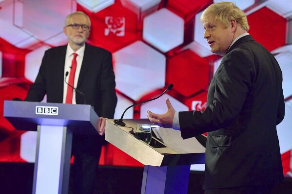 Opposition Labour Party leader Jeremy Corbyn, left, and Britain's Prime Minister Boris Johnson, during a head to head live Election Debate at the BBC TV studios in Maidstone, England, Friday Dec. 6, 2019.  Britain's Brexit is one of the main issues for political parties and for voters, as the UK prepares for a General Election on Dec. 12.  The debate is moderated by TV presenter Nick Robinson, right. ( Jeff Overs/BBC via AP)