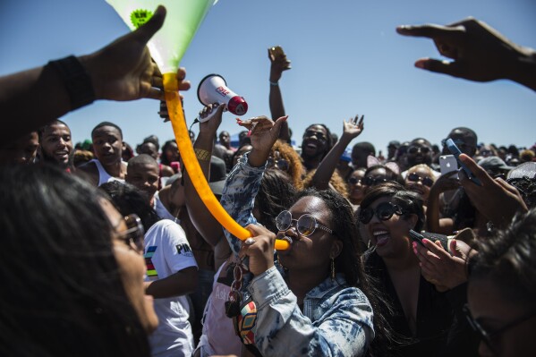 FILE - A crowd of party-goers cheer for a woman drinking from a beer bong during Orange Crush on Tybee Island, Ga., April 16, 2016. Thousands of Black college students expected this weekend for an annual spring bash at Georgia's largest public beach shouldn't expect a warm welcome. Tybee Island's city leaders are bringing in dozens of extra police officers and using barricades to block parking lots and residential streets during Orange Crush, a sprawling beach party begun three decades ago. (Josh Galemore/Savannah Morning News via AP, File)