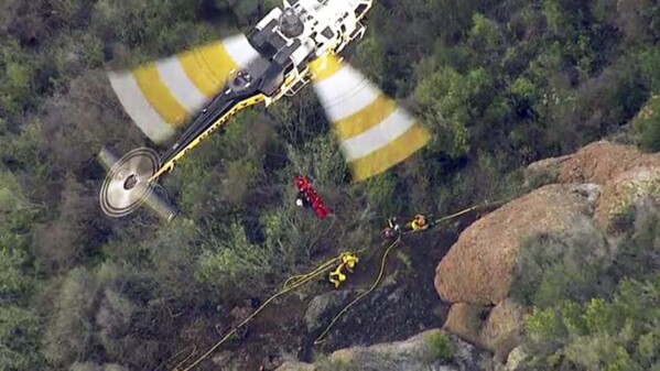 In this Feb. 25, 2016 still frame from video provided by KABC-TV, a Los Angeles County Fire Department helicopter lifts an inmate firefighter after she was injured fighting a brush fire in the Santa Monica Mountains above Malibu, Calif. California corrections officials say the firefighter, identified as Shawna Lynn Jones, died Feb. 26, a day after she was struck by a large rock while working the fire. (KABC-TV via AP)