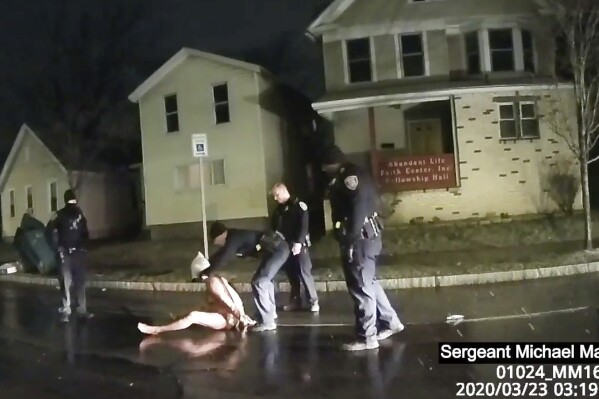 FILE- This image from police body camera video provided by Roth and Roth LLP, shows a Rochester police officer as he puts a hood over the head of Daniel Prude in Rochester, N.Y., March 23, 2020. Prude died after police held him down until he stopped breathing after encountering him running naked through the snowy streets of Rochester, NY. On Thursday, Oct. 12, 2023, a leading doctors group has formally withdrawn its approval of a 2009 paper on “excited delirium,” a document that critics say has been used to justify excessive force by police. (Rochester Police via Roth and Roth LLP via AP, File)