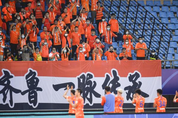 FILE - In this photo released by China's Xinhua News Agency, fans of Shandong Luneng cheer for their team after their Chinese Football Association Super League (CSL) match against Beijing Guoan in Suzhou in eastern China's Jiangsu Province, Oct. 17, 2020. Chongqing Liangjiang has withdrawn from the Chinese Super League just over a week before the start of delayed 2022 season in yet another setback for the domestic soccer scene. (Xu Chang/Xinhua via AP, File)