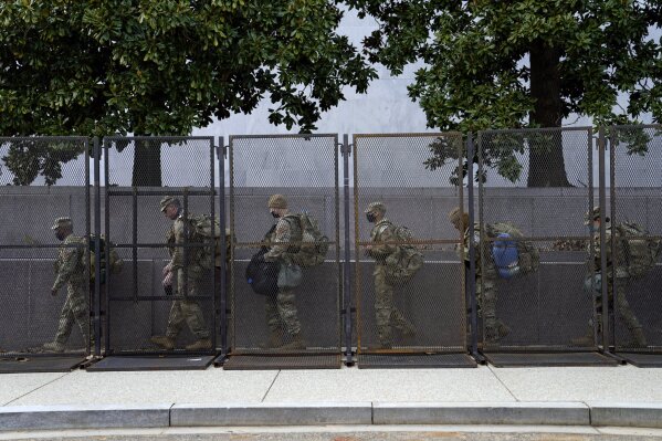 Troops walk behind security fencing on Saturday, Jan. 16, 2021, in Washington as security is increased ahead of the inauguration of President-elect Joe Biden and Vice President-elect Kamala Harris. (AP Photo/John Minchillo)
