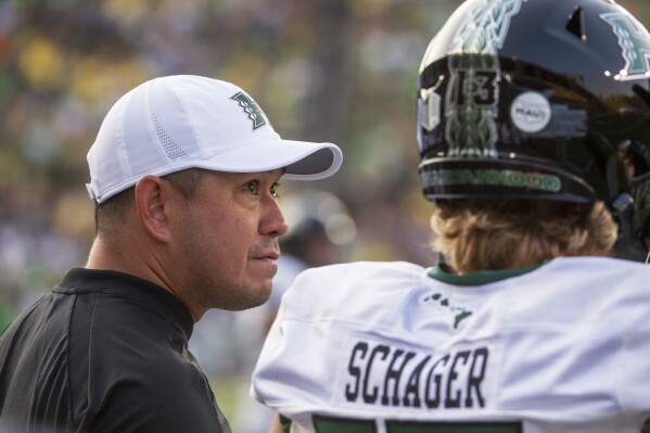 Hawaii coach Timmy Chang talks with quarterback Brayden Schager during the first half of the team's NCAA college football game against Oregon on Saturday, Sept. 16, 2023, in Eugene, Ore. (AP Photo/Andy Nelson)