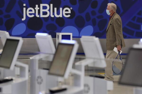 FILE - A traveler walks through the JetBlue terminal at Logan Airport in Boston, Friday, May 29, 2020. The government is getting its day in court to try to block a partnership between American Airlines and JetBlue. A trial is scheduled to start Tuesday, Sept. 26, 2022 in the Justice Department's antitrust lawsuit against the airlines. (AP Photo/Charles Krupa, File)