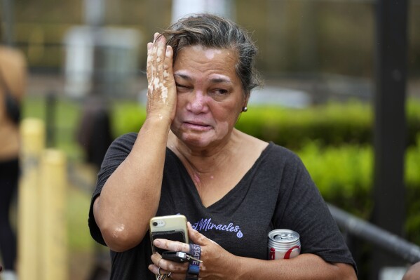 Myrna Ah Hee reacts as she waits in front of an evacuation center at the War Memorial Gymnasium, Thursday, Aug. 10, 2023, in Wailuku, Hawaii. The Ah Hees were there because they were looking for her husband's brother. Their own home in Lahaina was spared, but the homes of many of their relatives were destroyed by wildfires. (AP Photo/Rick Bowmer)