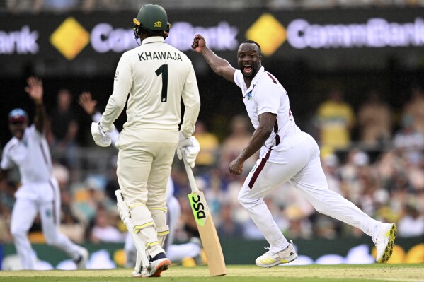 West Indies' Kemar Roach, right, celebrates after taking the wicket of Australia's Travis Head on the second day of their cricket test match in Brisbane, Friday, Jan. 26, 2024. (Darren England/AAP Image via AP)