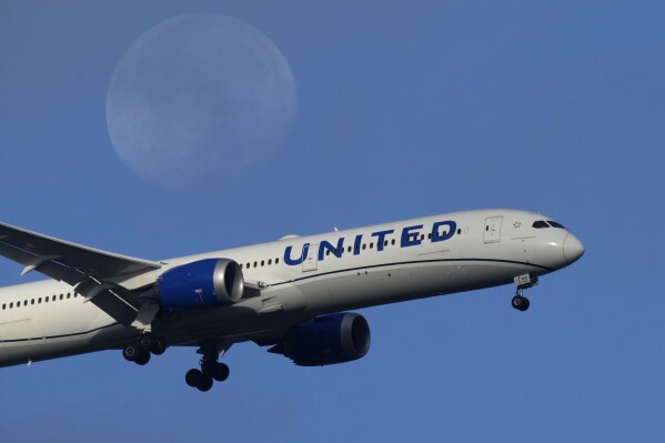 FILE - A United Airlines Boeing 787 approaches for landing in Lisbon, Sept. 2, 2023, with the setting moon in the background. United Airlines is making its second massive order of new planes in less than a year, more than 100 in all, as the carrier renews its fleet. The most recent order announced Tuesday, Oct. 3, will include 50 Boeing 787-9s for delivery between 2028 through 2031, and 60 Airbus A321neos for delivery between 2028 and 2030. (AP Photo/Armando Franca, File)