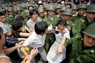 A young woman is caught between civilians and Chinese soldiers, who were trying to remove her from an assembly near the Great Hall of the People in Beijing, June 3, 1989. Pro-democracy protesters had been occupying Tiananmen Square for weeks. (AP Photo/Jeff Widener)