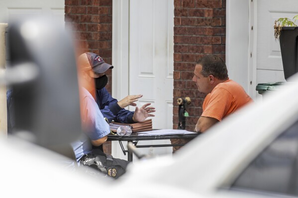 Brooks Hauck, right, talks with federal agents at his residence in Bardstown, Ky. Thursday, Aug. 6, 2020. Houck was arrested without incident on charges stemming from the Crystal Rogers investigation, Wednesday, Sept. 27, 2023. The indictment remains sealed and additional details will be revealed during Houck’s arraignment in early October in the Nelson County Circuit Court, according to a statement.(Jeff Faughender/Courier Journal via AP)
