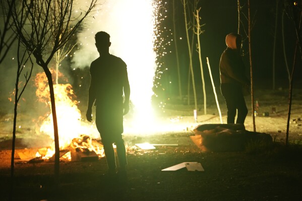 Iranians gather around a bonfire as they light a firework celebrating Chaharshanbe Souri, or Wednesday Feast, an ancient Festival of Fire on the eve of the last Wednesday of the Persian year, in Tehran, Iran, Tuesday, March 18, 2025. (AP Photo/Vahid Salemi)