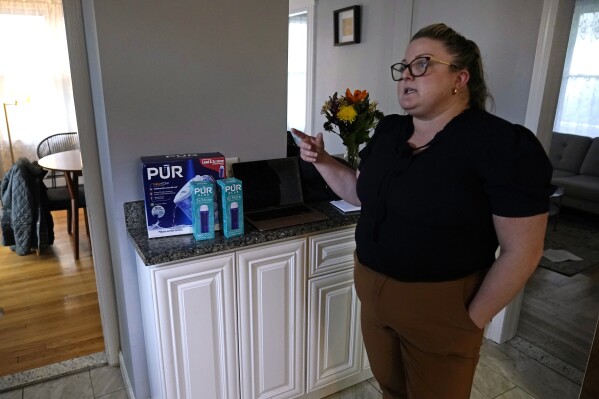 Colleen Colarusso, shows a water purification carafe and filters received from Providence Water after being alerted of health concerns from her residential water delivered through lead pipes, in the kitchen of her home, Thursday, March 23, 2023, in Providence, R.I. Testing showed lead levels in her water at more than twice the federal limit. Before that, she drank and cooked with tap water. (AP Photo/Charles Krupa)