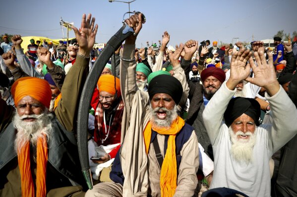 Protesting farmer leaders shout slogans as they sit on a day long hunger strike at the Delhi- Haryana border, outskirts of New Delhi, Monday, Dec.14, 2020. Tens of thousands of protesting Indian farmers have called for a national strike on Monday, the second in a week, to press for the quashing of three new laws on agricultural reform that they say will drive down crop prices and devastate their earnings. (AP Photo/Manish Swarup)