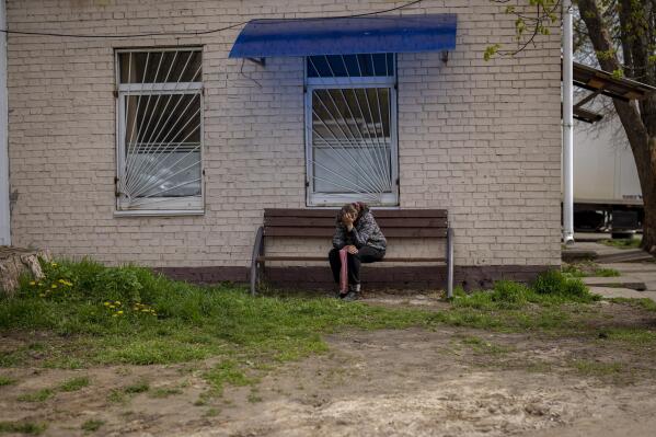Tetiana Boikiv, 52, center, sits on a bench as she waits for news of her husband, Mykola "Kolia" Moroz, 47, at the Bucha, Ukraine, morgue on Monday, April 25, 2022. Russian soldiers took Kolia from his house on March 15. He was tortured and shot, his body found two weeks later in a village 15 kilometers (9 miles) away where Russians set up a major forward operating base for their assault on the capitol, Kyiv. (AP Photo/Emilio Morenatti)