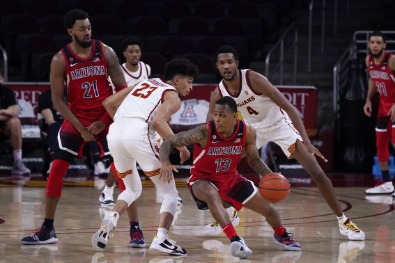 Arizona guard James Akinjo (13) dribbles around Southern California forward Max Agbonkpolo (23) during the second half of an NCAA college basketball game Saturday, Feb. 20, 2021, in Los Angeles. (AP Photo/Marcio Jose Sanchez)