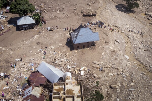 Survivors walk amidst debris next to destroyed buildings in the aftermath of floods in the village of Nyamukubi, South Kivu province, in Congo Monday, May 8, 2023. The death toll from floods in eastern Congo climbed to several hundred people as of Sunday, according to a local official. (AP Photo/Justin Kabumba)