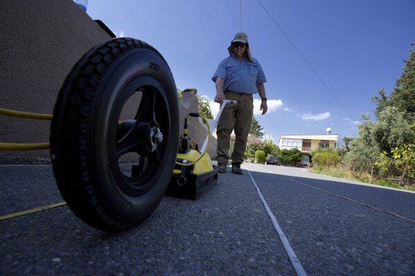 Harry M. Jol, a geography and anthropology professor at the University of Wisconsin Eau Claire, operates a ground-penetrating radar in the village of Exo Metochi, Duzova, in the Turkish occupied area at breakaway Turkish Cypriot north of ethnically divided Cyprus on Tuesday, Sept. 5, 2023. Emitting radio waves, the machine is probing for any disturbances through layers of soil beneath the asphalt to offer any clues supporting eyewitness accounts that people who vanished nearly a half century ago are buried in a makeshift mass grave, now squeezed between a two-story home and a fig orchard. (AP Photo/Petros Karadjias)