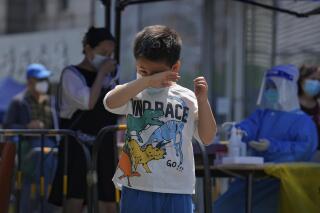 Un niño se frota los ojos tras someterse a una prueba de detección del coronavirus durante un cribado masivo, el 17 de mayo de 2022, en Beijing. (AP Foto/Andy Wong)