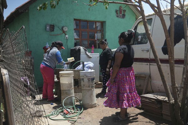 Raramuri Indigenous woman Gloria Vega, right, watches a neighbor wash clothes outside her home in Cuauhtemoc, Mexico, Thursday, May 1, 2025. (AP Photo/Martin Silva Rey)