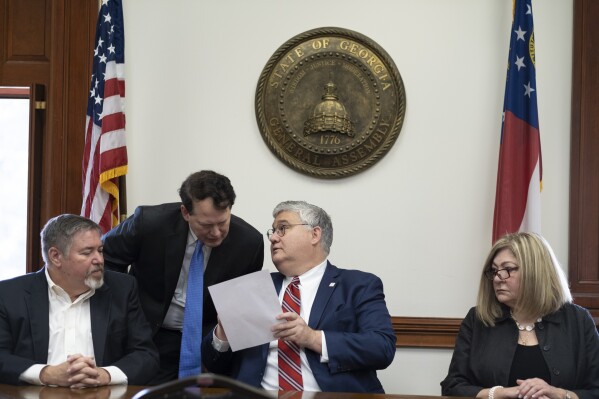 FILE – Then-Georgia Republican Party Chairman David Shafer (sitting) consults with Donald Trump reelection campaign lawyer Ray Smith during a meeting of Republican electors who cast votes for Trump and Vice President Mike Pence at the Georgia Capitol, Dec. 14, 2020, in Atlanta. The meeting of the electors has become a key element in the prosecution of Trump and 18 others in Georgia. Shafer and Smith are two of the four people present that day who was indicted by a Fulton County grand jury in August 2023 on charges that he conspired to illegally overturn Democrat Joe Biden's win in Georgia. (AP Photo/Ben Gray, File)