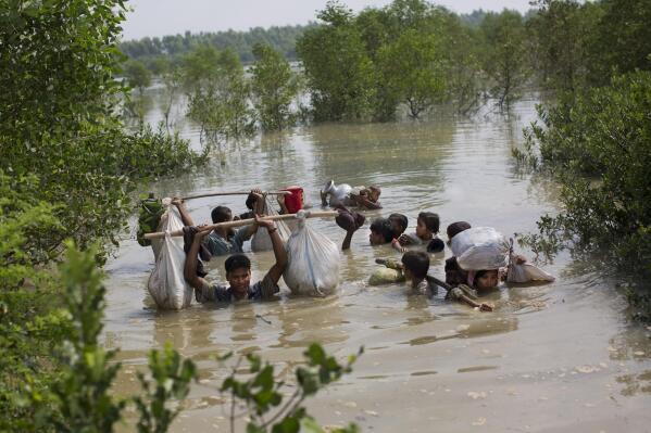 FILE- A Rohingya family reaches the Bangladesh border, Tuesday, Sept. 5, 2017, after crossing a creek of the Naf river on the border with Myanmmar, in Cox's Bazar's Teknaf area. Judges at the International Court of Justice rule Friday July 22, 2022, on whether a case brought by Gambia alleging that Myanmar is committing genocide against the Rohingya can go ahead. Myanmar argues that the court does not have jurisdiction. (AP Photo/Bernat Armangue, file)