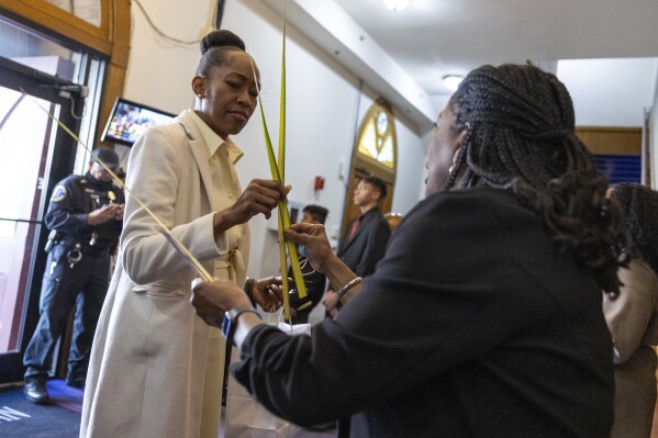 Wanda Dorsey-Jenkins takes a palm frond from greeter Robin Ford before Palm Sunday services at the Metropolitan AME Church in Washington, Sunday, March 24, 2024. As Black Protestants prepare for Easter this year, they hope to welcome more people to church than since the COVID-19 pandemic began four years ago. (AP Photo/Amanda Andrade-Rhoades)