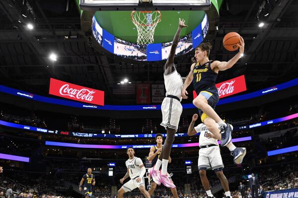 Marquette guard Tyler Kolek (11) goes to the basket against Georgetown forward Akok Akok, center, during the second half of an NCAA college basketball game, Saturday, Feb. 11, 2023, in Washington. Marquette won 89-75. (AP Photo/Nick Wass)